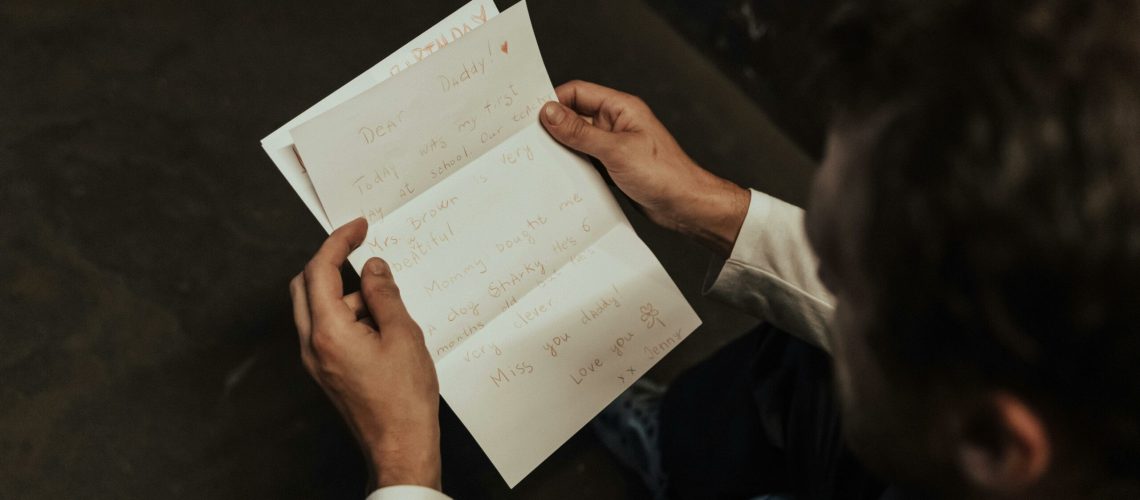 Un homme est assis à une table il lit une lettre dans un processus de reconquête.
